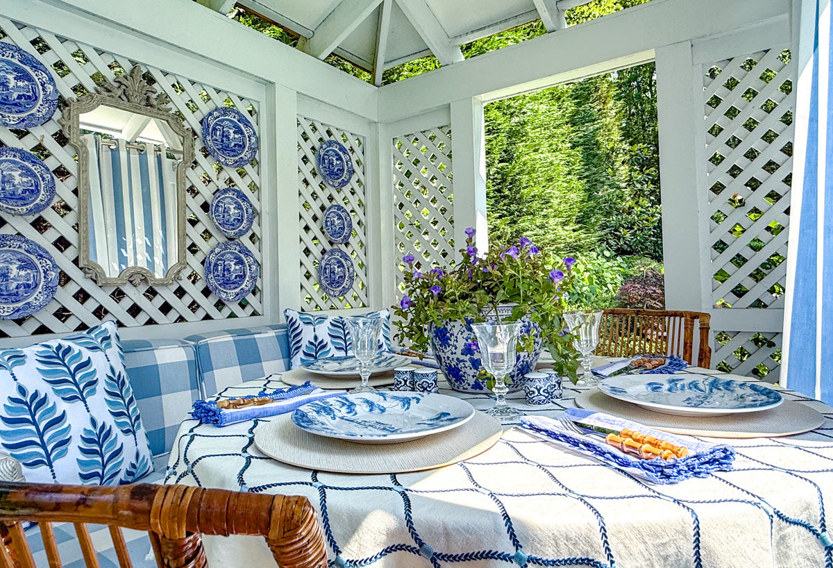 Designer styling chinoiserie in modern gazebo table with ginger jars, porcelain plates, and blue and white table linens