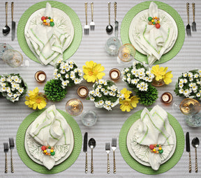 Overhead view of a table with four place settings featuring placemats and Kim Seybert Luxury Filament Napkin in white, yellow & green 