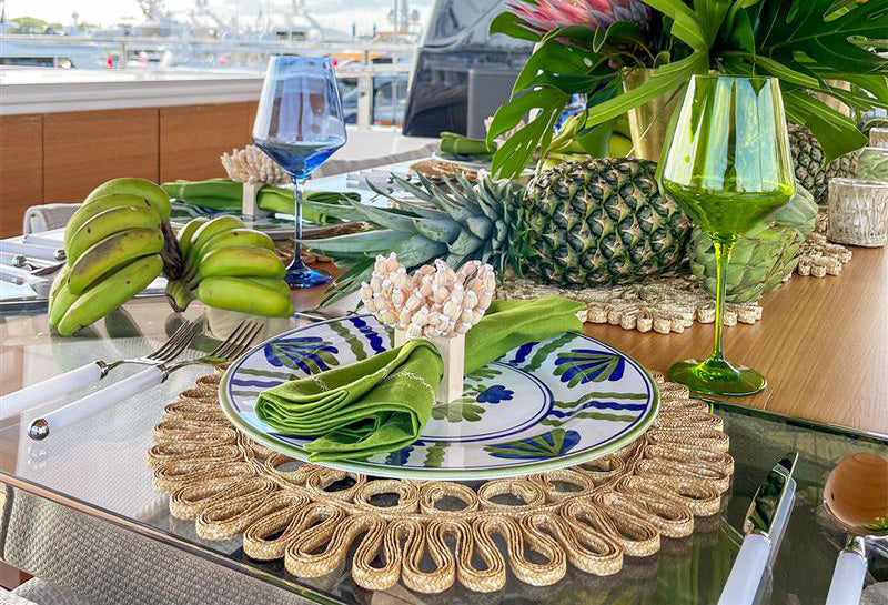 Luxury tableware for your yacht with tropical dinnerware, organic woven placemats, and a fresh pineapple centerpiece