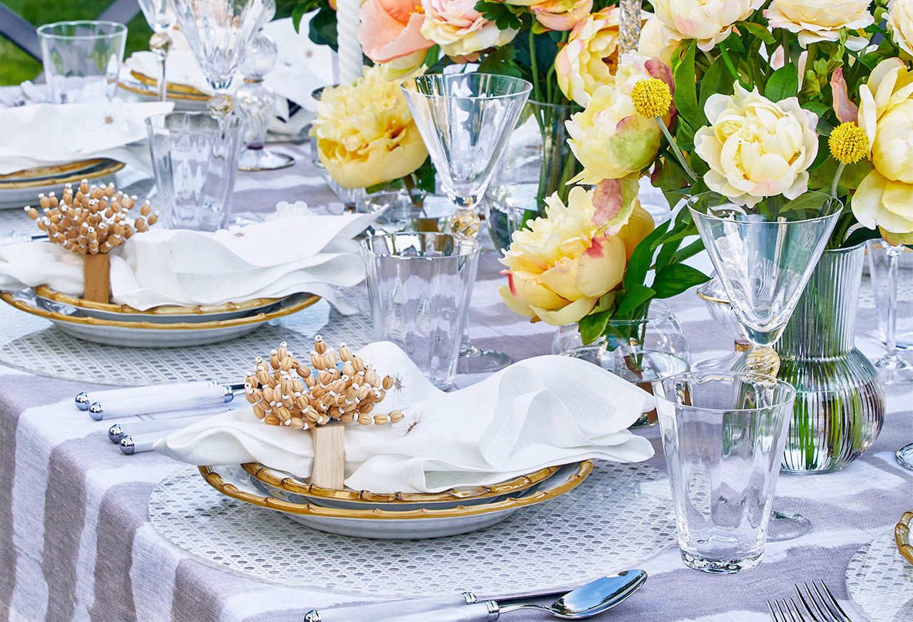 Close-up of a Kim Seybert-designed table setting with flower centerpieces illustrating how to keep flowers fresh in a vase