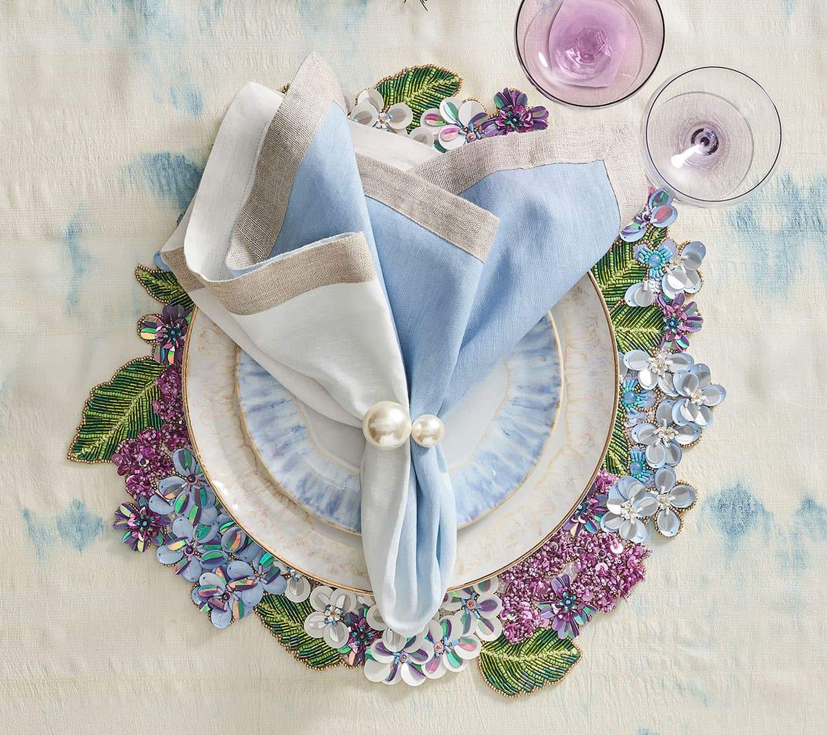 Hydrangea Placemat with white, blue and purple florals underneath white and blue plates and a white & blue napkin