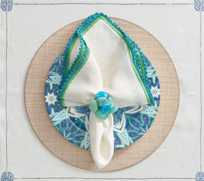 Round Portofino Placemat in natural underneath a blue and green patterned plate and a napkin ring with a blue & green border 