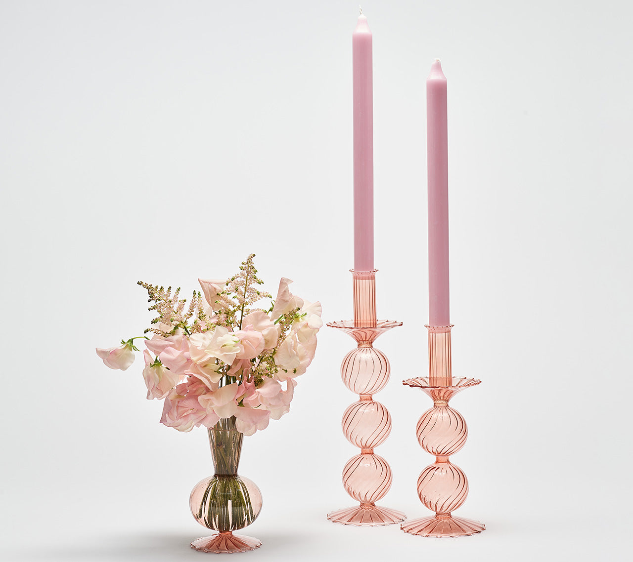 Two Bella Candle Holders in blush next to a Tess Bud Vase in blush with similar-color flowers