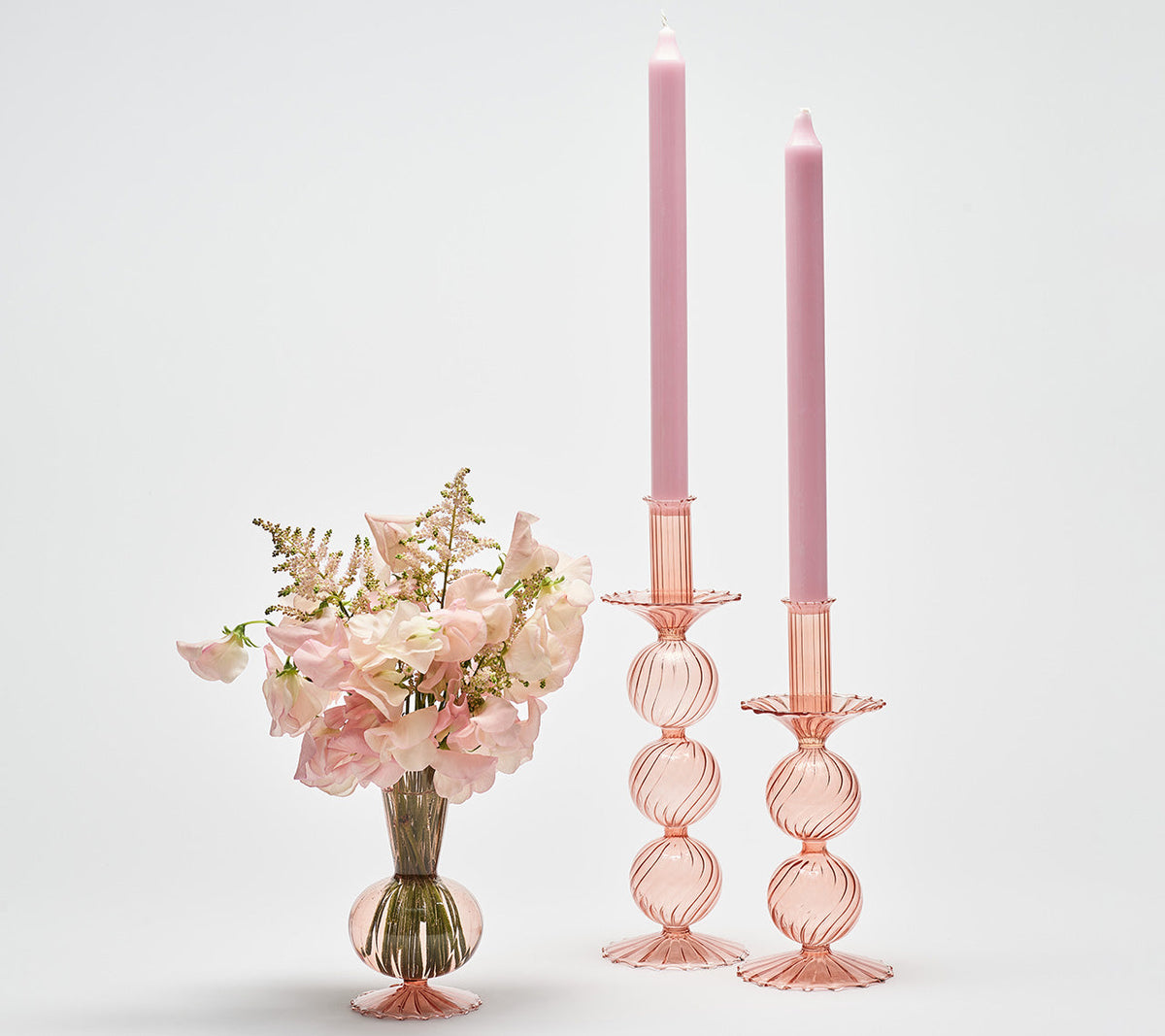 Two Iris Tall Candle Holders in blush next to a vase with blush flowers