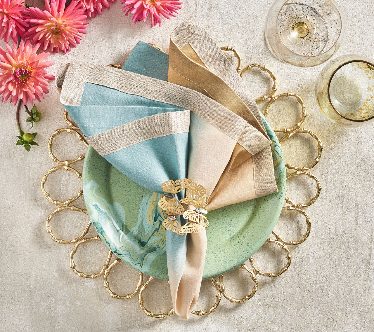 Overhead view of Kim Seybert Luxury Dip Dye Napkin in natural & seafoam on a green plate and gold placemat