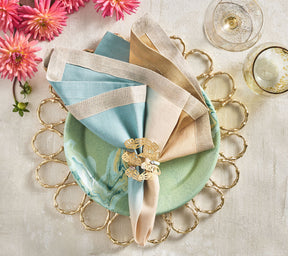 Kim Seybert Luxury Dip Dye Napkin in natural & seafoam on a green plate and gold placemat