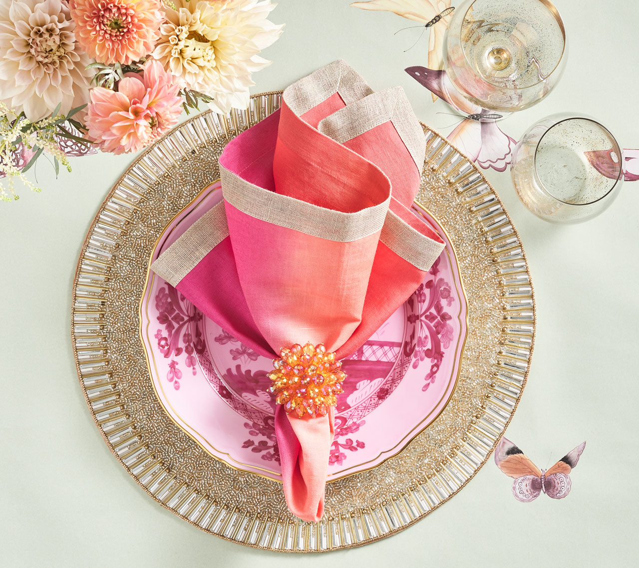 Place setting with a gold beaded placemat, pink plate and napkin held by a pink & orange Zinnia Napkin Ring 