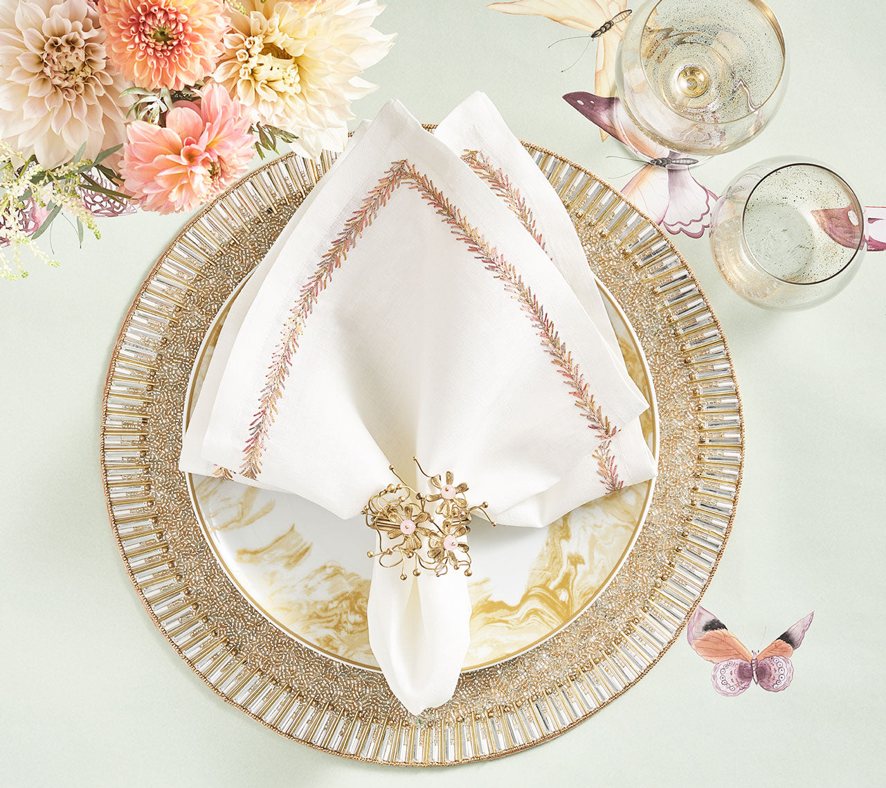 Round Bevel Placemat in gold & silver underneath similar-toned plates, napkin, and napkin ring