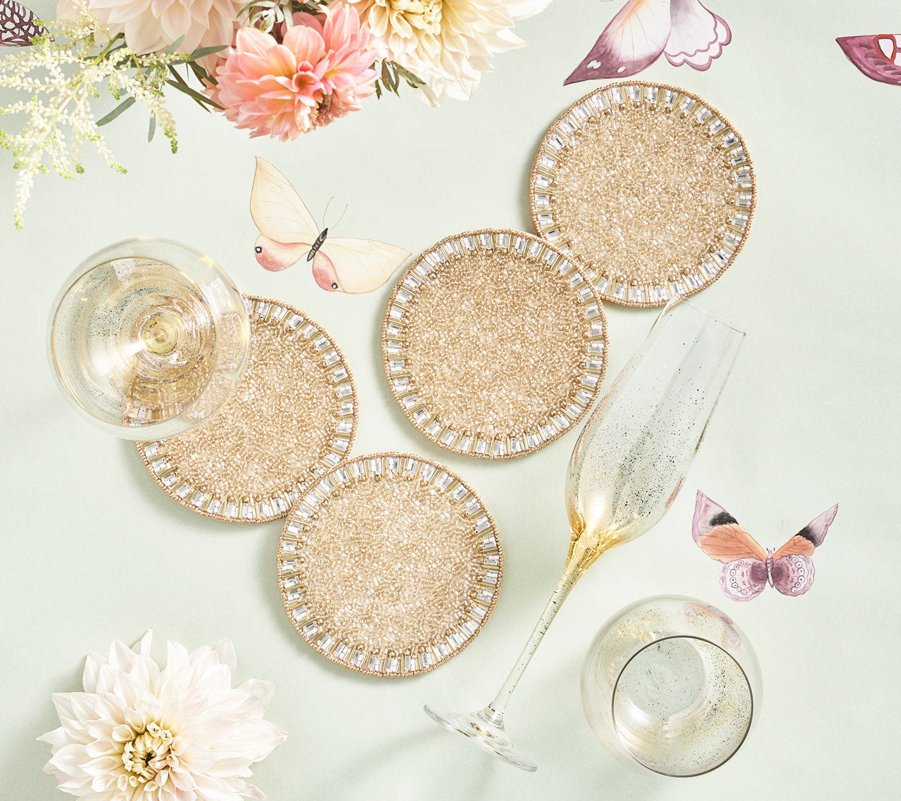 Beaded Bevel Drink Coasters on a table with champagne glass and butterfly tablecloth