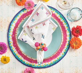 Kim Seybert Luxury Fez Napkin in white & multi on a colorful beaded placemat 