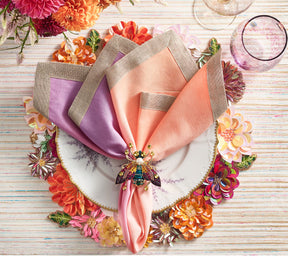 Colorful Dahlia Placemat with florals of pink, orange, and amethyst beneath a peach & lilac napkin held by a jeweled insect napkin ring