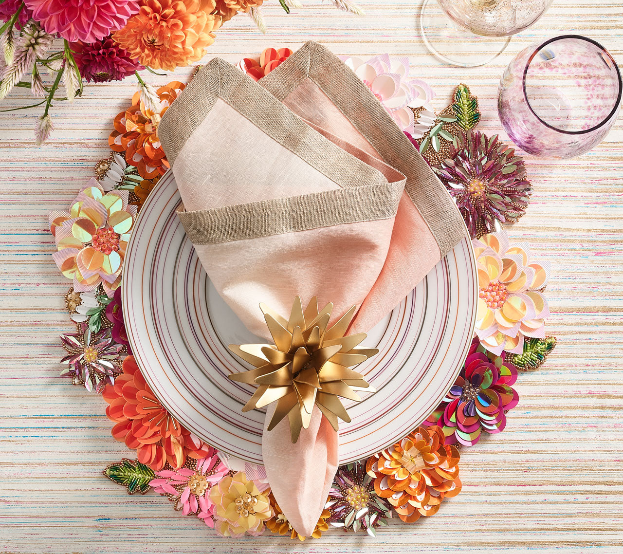 Floral Dahlia Placemat in shades of pink, amethyst, and orange beneath a plate and pink ombre napkin