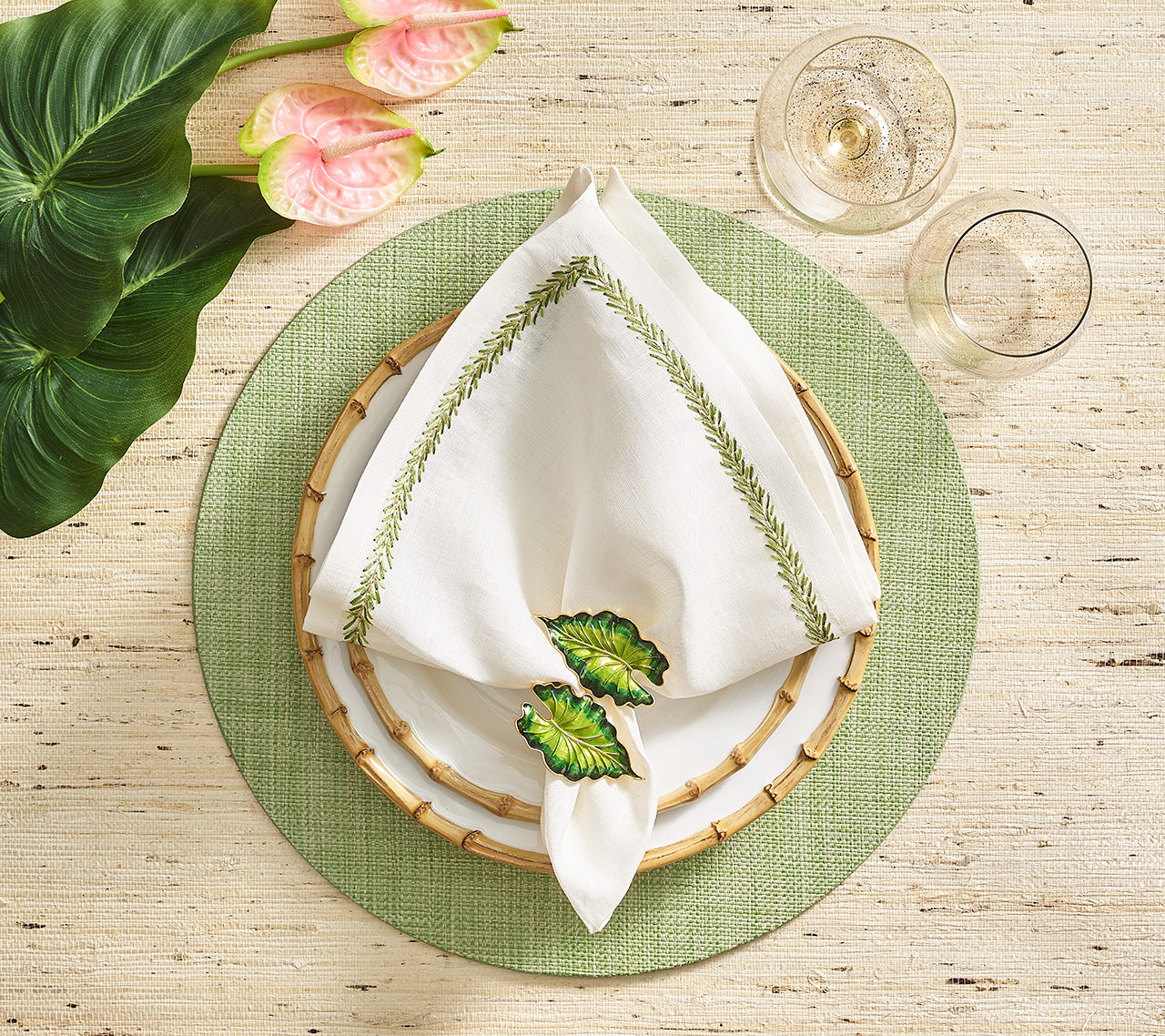 Green Portofino Placemat underneath a bamboo-rimmed plates and a white napkin held by a green leaf napkin ring