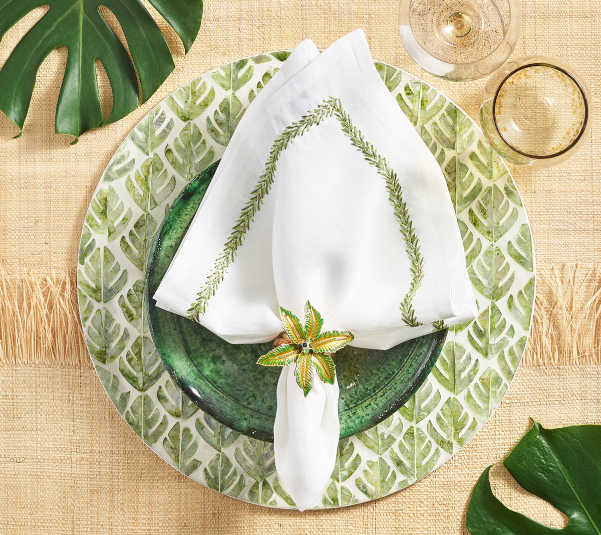 Green & Gold Palm Coast Napkin Ring holding a white napkin on top of a palm-inspired placemat
