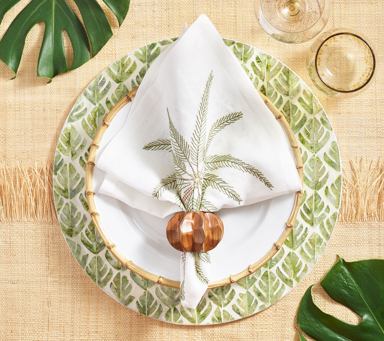 Fern Placemat in ivory & green underneath a bamboo-rimmed plate and white napkin with greenery