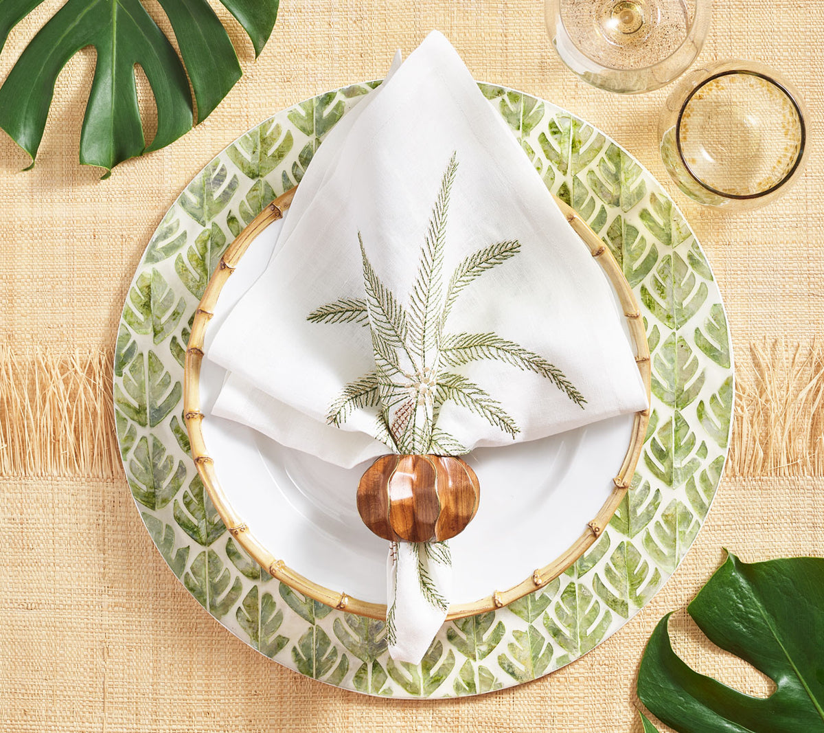Round placemat with palms below a white Palm Coast Napkin with green & gold palm frond