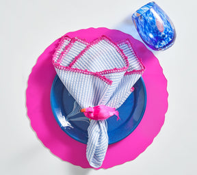Periwinkle & pink Seersucker Napkin atop a blue plate and pink placemat
