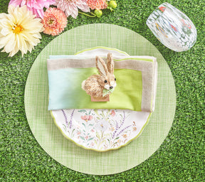 Spring place setting with a green Portofino Placemat beneath a floral plate, pastel napkin and bunny napkin ring