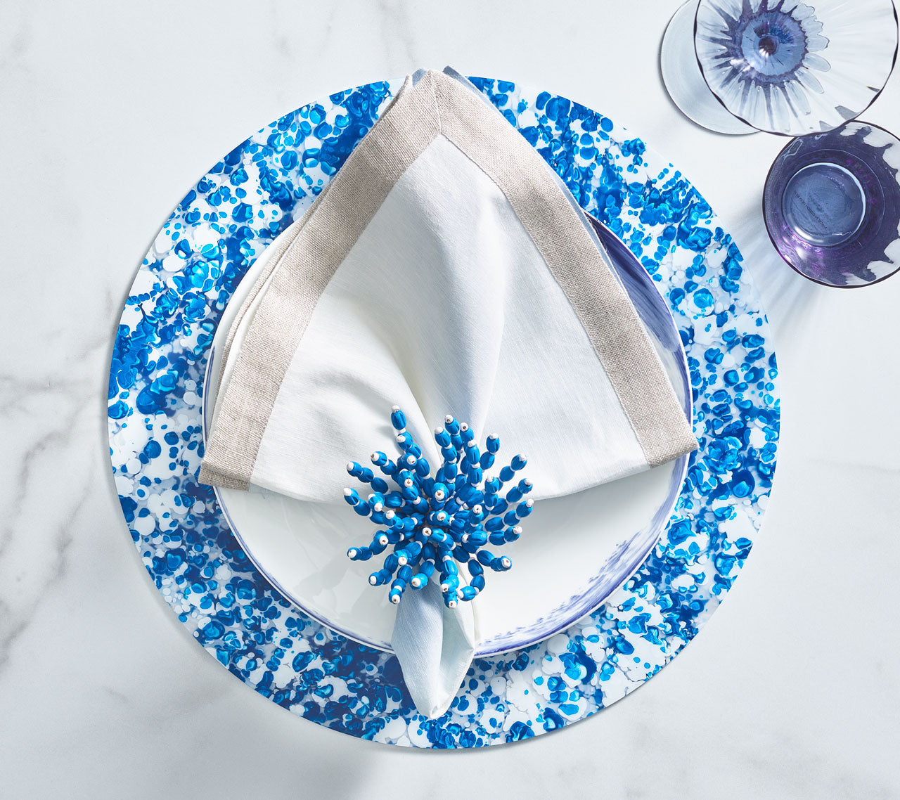 Blue Reed Napkin Ring holding a white napkin atop a blue & white placemat