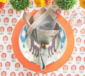 Kim Seybert Luxury Croco Placemat in orange on a table with a white and orange tablecloth