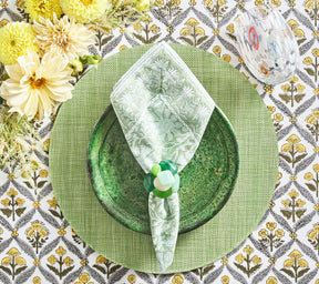 Place setting with a green  placemat, plate, and napkin, which is held by a green Sea Stone Napkin Ring 