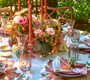 Kim Seybert Luxury Bella Short Candle Holder in blush featured on a table outside 