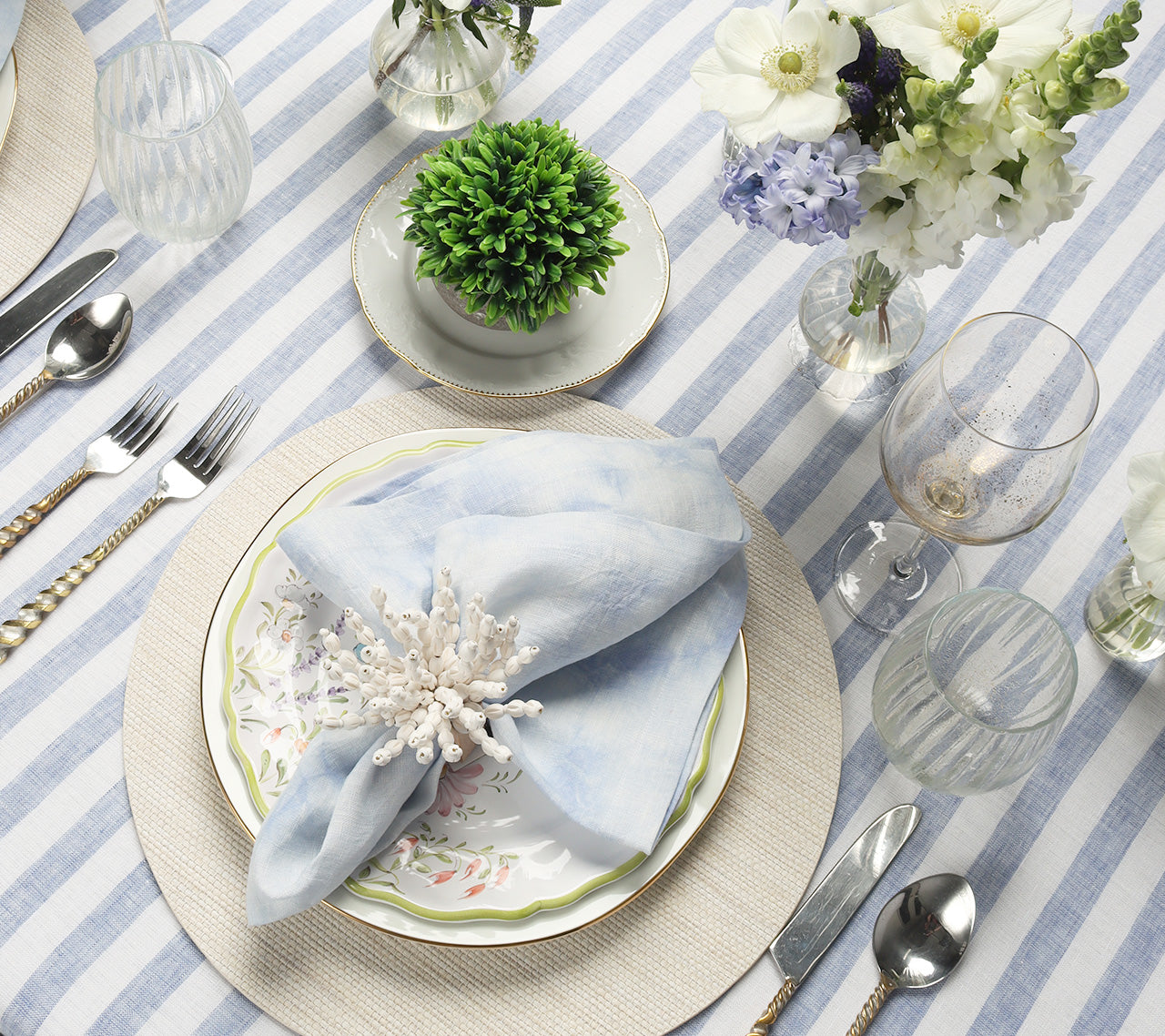 Table set with blue-and-white striped tablecloth, natural-color placemat and a periwinkle Cloud Napkin 