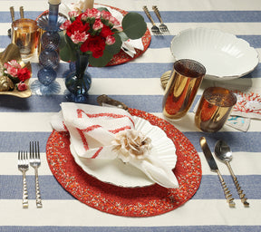 Table with blue-and-white striped tablecloth, a red placemat, and two Iris Tall Candle Holder in cadet blue