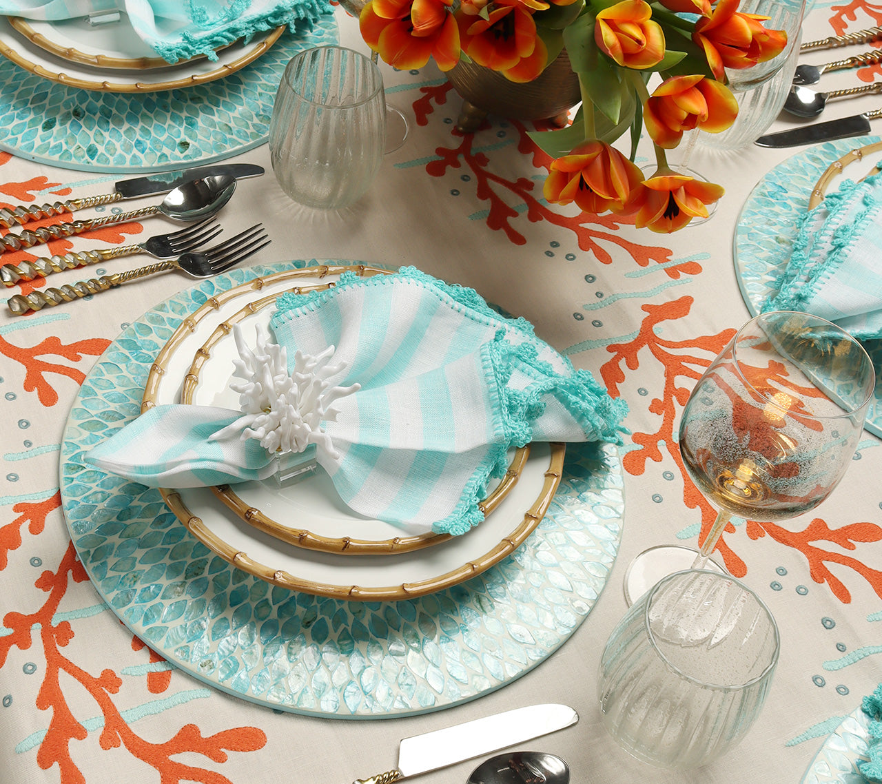 Seafoam Marquis Placemat on a table with a cream tablecloth with an orange coral motif