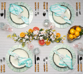 Tablescape with four Tahiti Placemat in periwinkle, a citrus centerpiece, bamboo-handle cutlery, and aqua & white napkins