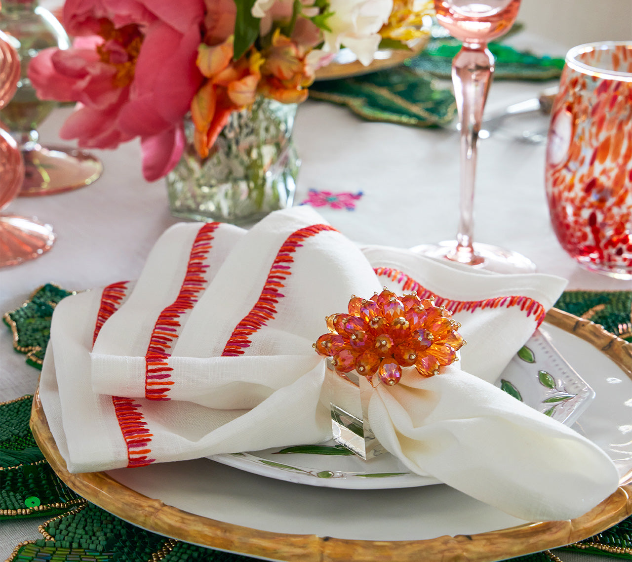 Up close view of a plate with a white napkin held by an orange and pink Zinnia Napkin Ring 