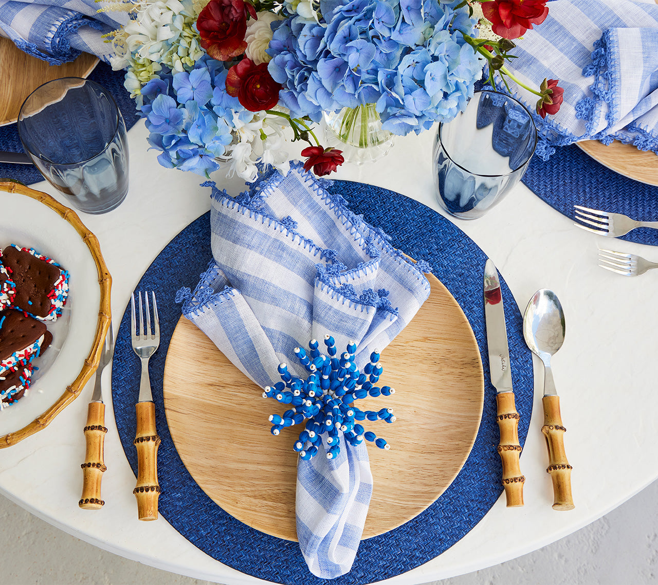 Place setting featuring a Kim Seybert Luxury Linea Napkin in white & blue with blue hydrangea
