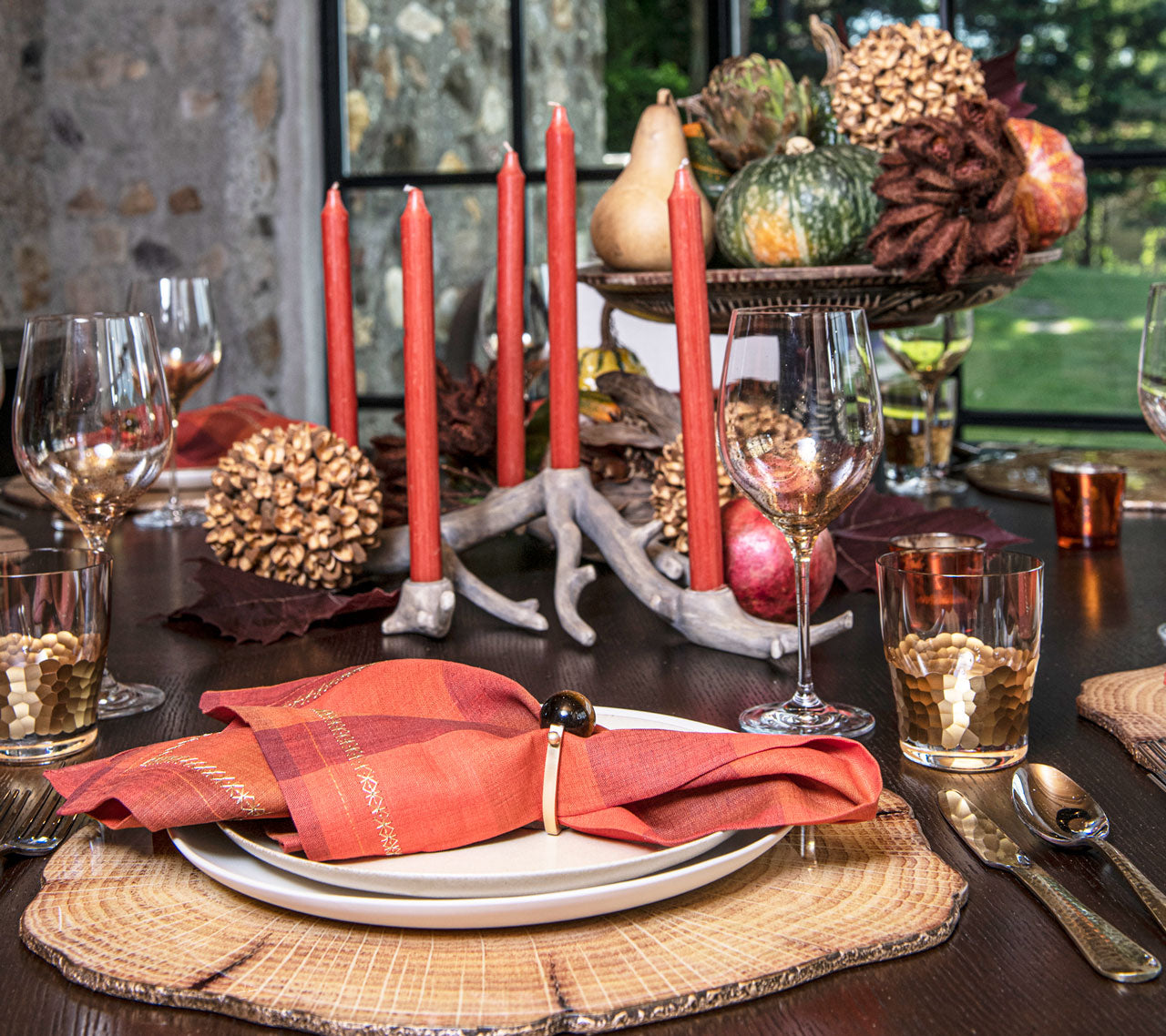 Side view of a wooden table with coral candles, fall decorations and a coral napkin on top of a Woodland Placemat in natural & brown