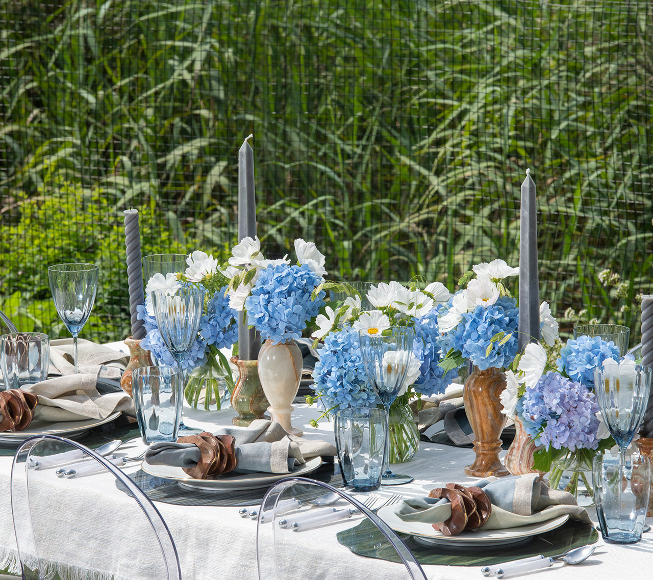 Outdoor table with vases of blue hydrangea and place settings with brown napkin rings and Dip Dye Napkins in natural & seafoam 