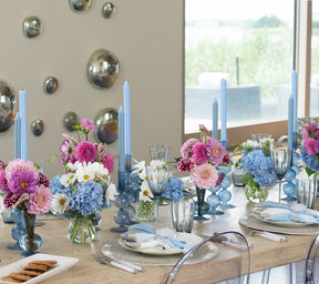 Table with a center that has blue Bella Candleholders and blue Tess Bud Vases with pink flowers
